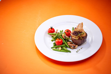 steak with vegetables on the orange background