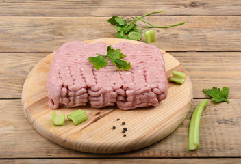 Minced turkey with parsley, celery and pepper on a wooden cutting board.