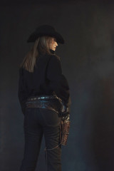 Blonde cowgirl in black hat wearing holster.