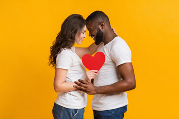 Romantic Interracial Couple Holding Red Paper Heart And Touching Foreheads