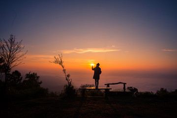 Silhouette of a girl  in front of the sunset on the hill.
