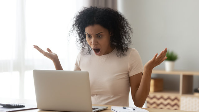 Amazed shocked african woman open mouth gawp at computer screen