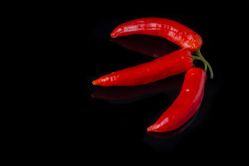 Three red chili peppers. Hot spicy chili peppers on black background. Space for text.