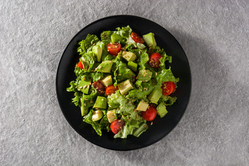 Salad with avocado, lettuce, tomato and flax seeds on gray background Top view. 	