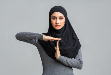 Serious islamic girl showing time out gesture, demonstrating time break sign
