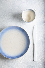 White with blue empty plate with cutlery on marble table. Marble background. Copyspace. Top view.