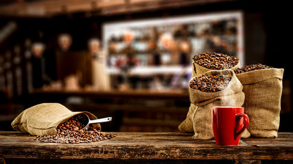 Wooden board of free space for your decoration and fresh coffee beans in brown sacks. 