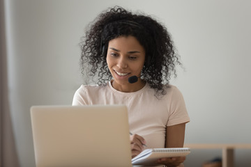African woman in headset looking at computer do online task