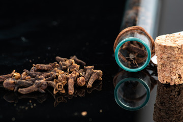 dried clove spice next to test tube and cork