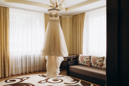 Bride's dress with plume hangs on a chandelier
