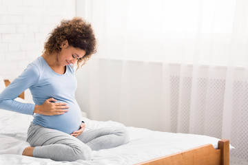 Pretty afro pregnant woman keeping hands on belly