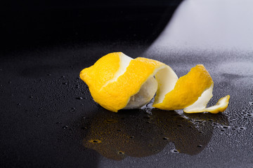Peeled lemon on wet surface. Undressed citrus in the darkness. Food concept.