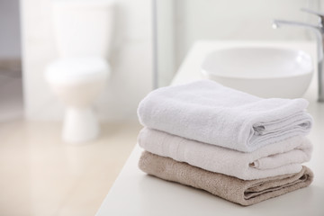Stack of fresh towels on countertop in bathroom. Space for text - obrazy, fototapety, plakaty