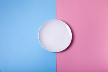 Empty white plate on blue and pink pastel background