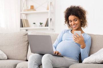 African-american pregnant girl using laptop and cellphone
