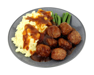 Beef meatballs and mashed potato meal with green beans and gravy isolated on a white background