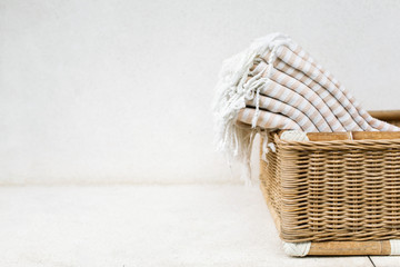 White stripe cotton bath towels lying in whicker basket on white background. Organic pestemal towels made of natural eco materials.
