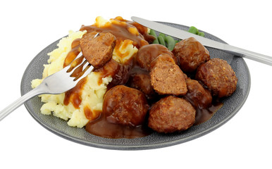 Beef meatballs and mashed potato meal with green beans and gravy isolated on a white background