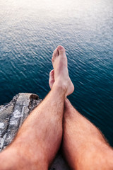 Legs of a man resting on the sea with a village