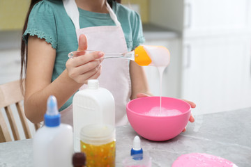 Obraz na płótnie Canvas Little girl mixing ingredients with silicone spatula at table in kitchen, closeup. DIY slime toy