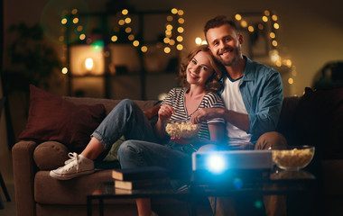 Family couple watching television projector at home on sofa.