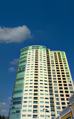 Fototapeta na wymiar Condo Tower with Green Windows into Blue Sky
