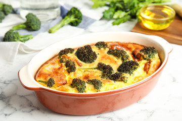 Tasty broccoli casserole in baking dish on white marble table