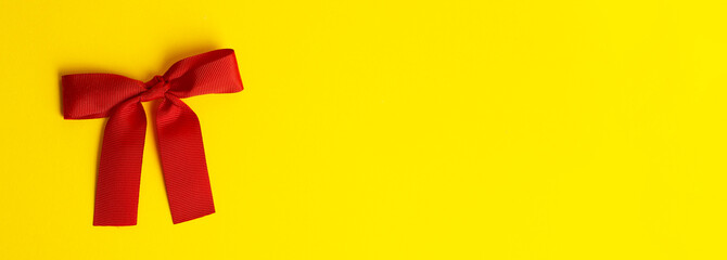 Gift bow on a yellow banner background. Red gift bow with shadow on a colored yellow background....