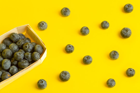 Blueberry berries on a yellow background. A scattering of berries on a colored yellow background. Minimal food and summer concept