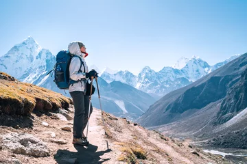 Papier Peint photo Ama Dablam Young hiker backpacker female taking a walking with trekking poles during high altitude Everest Base Camp route near Dingboche,Nepal. Ama Dablam 6812m on background. Active vacations concept