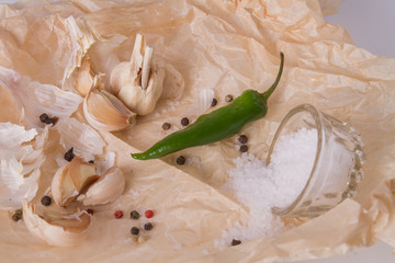 Green chili pepper with garlic. Coarse salt on parchment. Pepper background.
