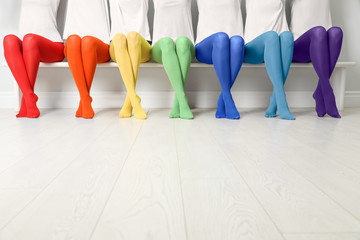 Women in different colorful tights sitting on bench, closeup