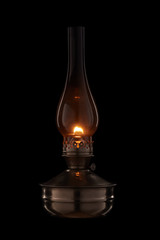 Vintage kerosene lamp burning on black background. Glass old oil lamp.