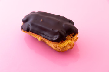 Chocolate covered cake and cream filling on pink background