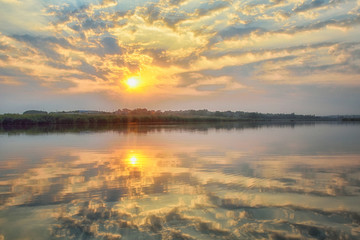 Beautiful panorama of the river landscape. Reflection of the sky and the sun in the water.