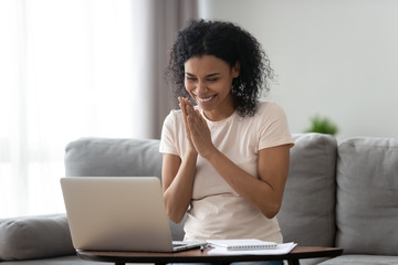 African woman looking at laptop received promotional offer feels happy