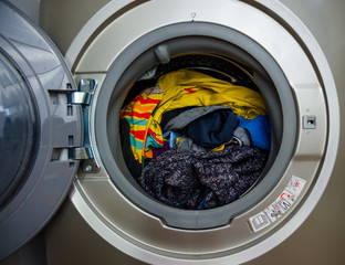 Washing machine with dryer, freshly washed clothes and dried in combined washing machine. Colored clothes, open doors, rubber seal, stainless drum, clean clothes