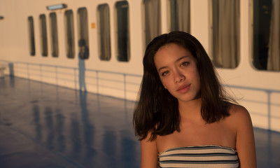 Closeup of Asian teen on in tube top on Ferry boat with windows in the background