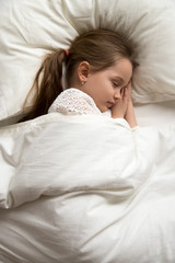 Obraz na płótnie Canvas Calm child, little girl sleeping in comfortable bed vertical photo