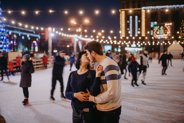 Young couple skates at the rink and kisses.