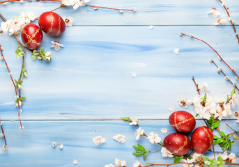 Easter eggs and spring white flowers and willow branches on Easter blue wood background with copy...