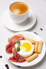 fried eggs with meat and bread on a white plate on a white plate and black coffee close-up