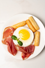 fried eggs with meat and bread on a white plate on a white plate