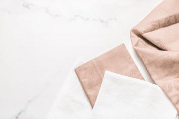 Kitchen textile on chic white marble background, napkin and towel set, folded fabrics as food...