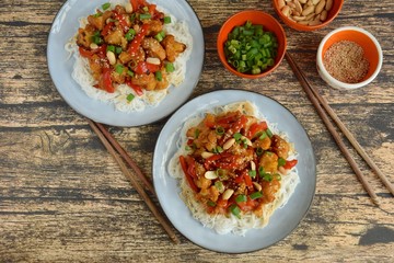 Cauliflower Kung Pao with bell pepper and rice noodles. Garnish with peanuts, scallions and sesame seeds. Vegan food