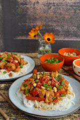 Cauliflower Kung Pao with bell pepper and rice noodles. Garnish with peanuts, scallions and sesame seeds. Vegan food
