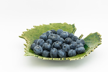 dojrzałe jagody borówki  na  zielonym talerzyki listku  © Joanna