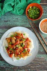Cauliflower Kung Pao with bell pepper and rice noodles. Garnish with peanuts, scallions and sesame seeds. Vegan food