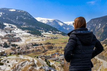 Naklejka premium Young tourist woman and winter snow landscape mountain view in Andorra, Pyrenees mountains, Europe. Andorra is perfect tourist travel destination. Luxury amazing resort for skiing and winter travel