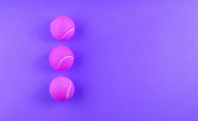 Three pink Tennis balls on purple abstract background. Game concept